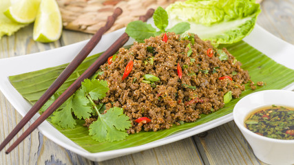 Wall Mural - Larb - Lao minced beef salad with fish sauce, lime juice, roasted ground rice and fresh herbs served with lettuce leaves for wraps.