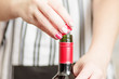 Female unscrews the screw cap wine bottle