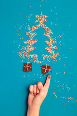 Awaiting for Christmas. Symbols of christmas tree and gifts made of colored sprinkles on blue background