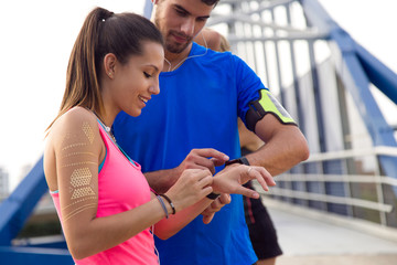 Outdoor young couple using they smartwatch after running.