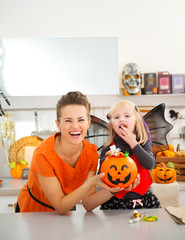 Wall Mural - Happy mother with daughter in bat costume eating halloween candy