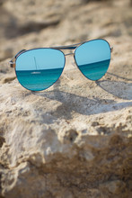 Blue Mirrored Sunglasses On The Beach Background Close Up