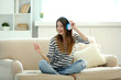 © Africa Studio - Woman listening music in headphones in room