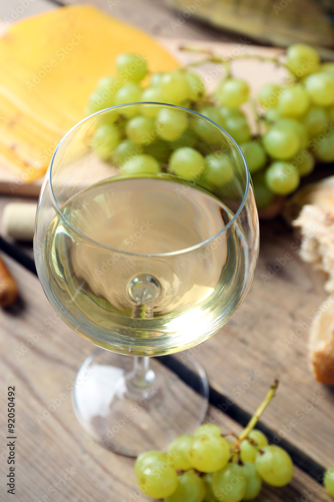 Still life of wine, grape, cheese and bread on rustic wooden background