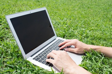 Young Asian freelance man using a pc at a park