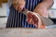 Close up of butcher carving raw lamb