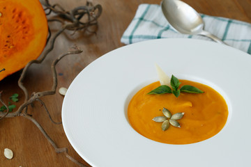 squash soup in a plate with basil leaf