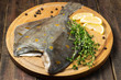 Raw plaice with pepper, thyme and lemon on the board