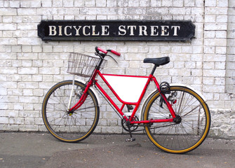 Bicycle Street sign with a bicycle leaning against a wall with an empty panel for your logo or message