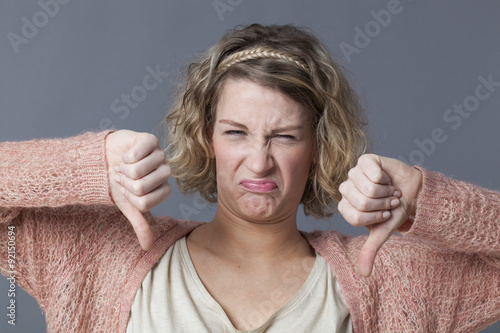 grumpy girl expressing disgust,disagreement and dislike with thumbs down Tableau sur Toile
