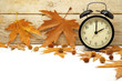 Autumn Time Change / Fall Back / Maple Leaves and an Alarm Clock on a Wooden Background