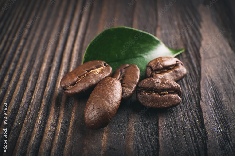 Coffee beans with leaf on wooden background