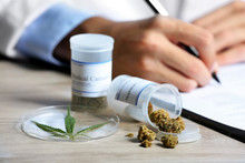 Doctor Writing On Prescription Blank And Bottle With Medical Cannabis On Table Close Up