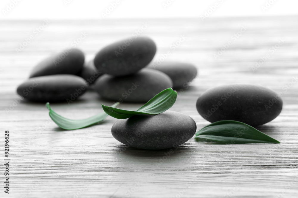Spa stones with green leaves on wooden background