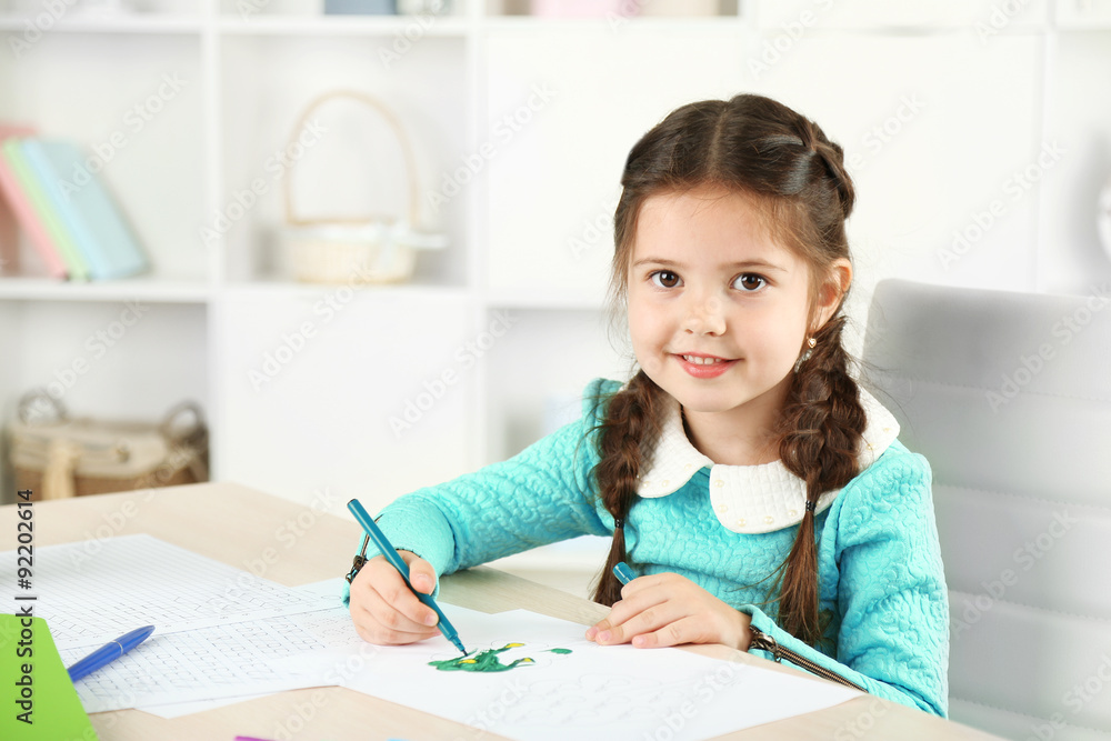 Cute little girl doing her homework, close-up, on home interior background