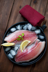 Sticker - Frying pan with fresh iced tilapia filets, top view, studio shot