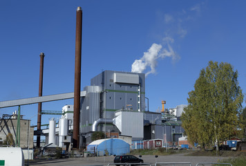 A factory with chimneys and smoke on a blue sky