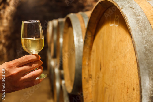 Photo Hand holding a glass of white wine in cellar