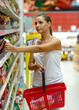 © vladstar - Young woman shopping for cereal, bulk in a grocery supermarket