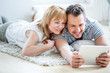 © tunedin - Paar mit Tablet liegt auf Boden und surft im Internet