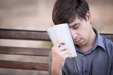 Upset man with the bible on the bench