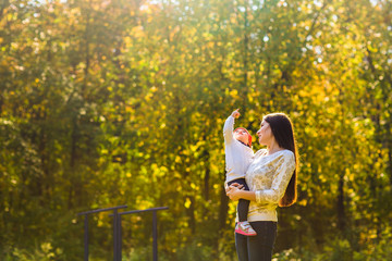 Wall Mural - Young mother walking with her baby in an autumn park