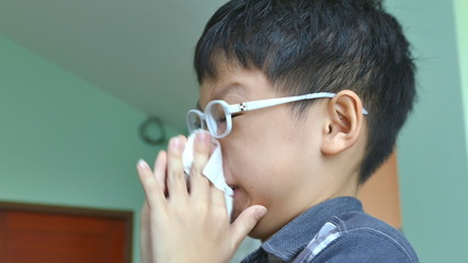 Wall Mural - Young Asian boy wipes his snot by tissue paper 
