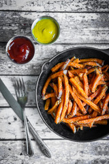 Wall Mural - Sweet potato fries in cast iron skillet on wooden background