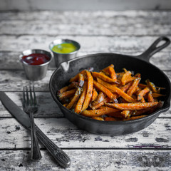 Wall Mural - Sweet potato fries in cast iron skillet on wooden background