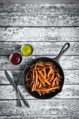 Wall Mural - Sweet potato fries in cast iron skillet on wooden background