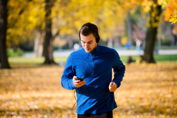 Wall Mural - Man jogging and checking mobile phone