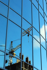 reflection of the sky in the glass windows of the crane construction