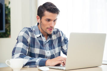 Wall Mural - Man using laptop with headphones at home