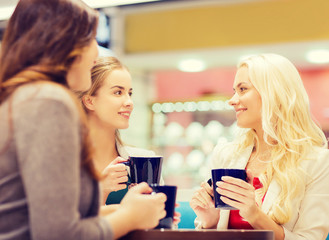 Canvas Print - smiling young women with cups in mall or cafe