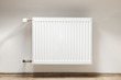 Heating radiator in a white room with laminated wooden floor