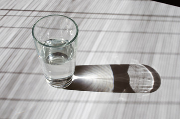 Glass of water lightened with sun on a white table