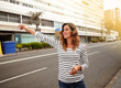© pablocalvog - Cheerful young woman hailing a cab on city street