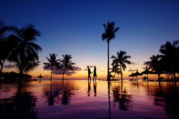 Wall Mural - Silhouettes of young couple at scenic sunset