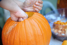 A Man Pulls Seeds And Fibrous Material From A Pumpkin Before Carving For Halloween.