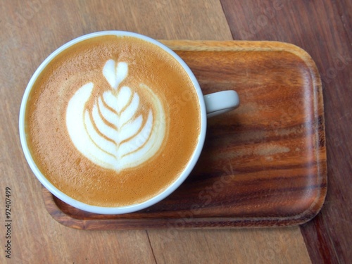 Fotografie, Obraz flat white coffee with latte art, this pattern is commonly called "tulip" on wooden saucer and table in cafe