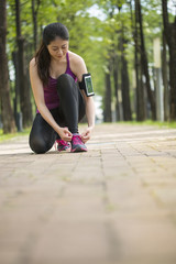 Wall Mural - Asian young woman runner tying shoelaces healthy lifestyle