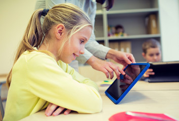 little girl with teacher and tablet pc at school