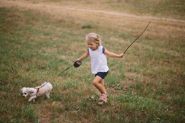 Beautiful little girl walking her dog in the park