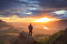 Hiker Standing On A Ledge Of A Mountain, Enjoying The Beautiful Sunset Over A Wide River Valley In Thorsmork, Iceland.
