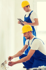 Canvas Print - builders with tablet pc and fixing wiring indoors