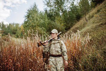 man hunter with shotgun in forest