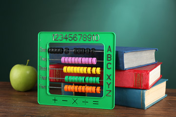 Poster - Colorful abacus with stack of book sand green apple on desk on green chalkboard background