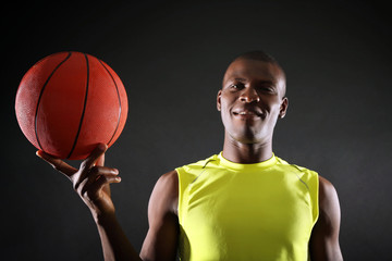 Wall Mural - African American basketball player holding ball on dark background