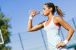 Young beautiful athlete drinking water after exercising