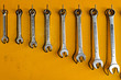 Metal wrenches hanging on a yellow board wall